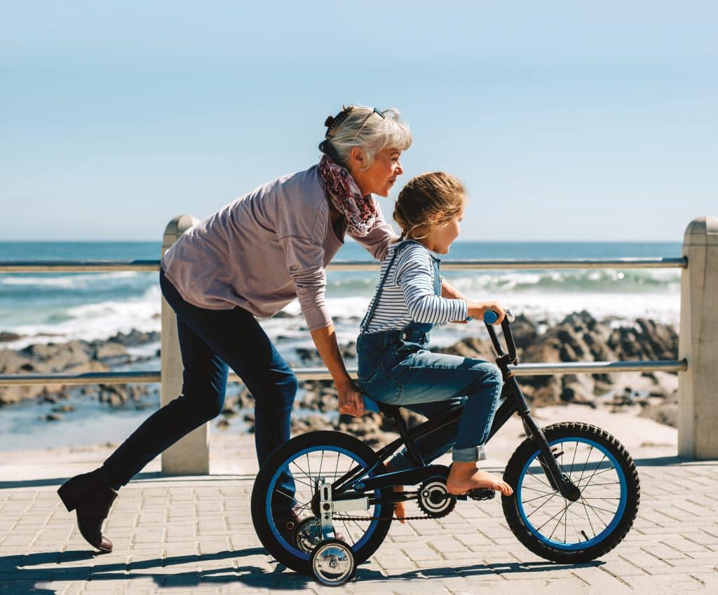 Senior woman teaching a small girl to ride a bicycle