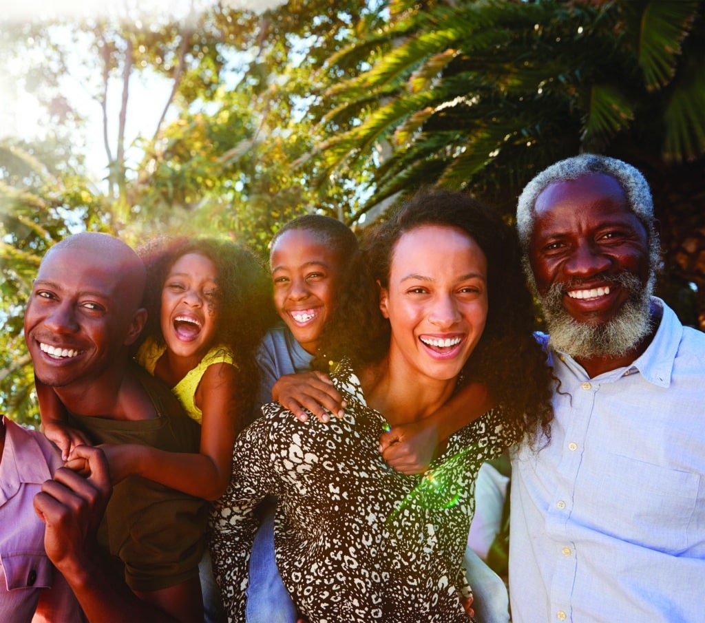 Outdoor Portrait Of Multi-Generation Family In Garden At Home Against Flaring Sun